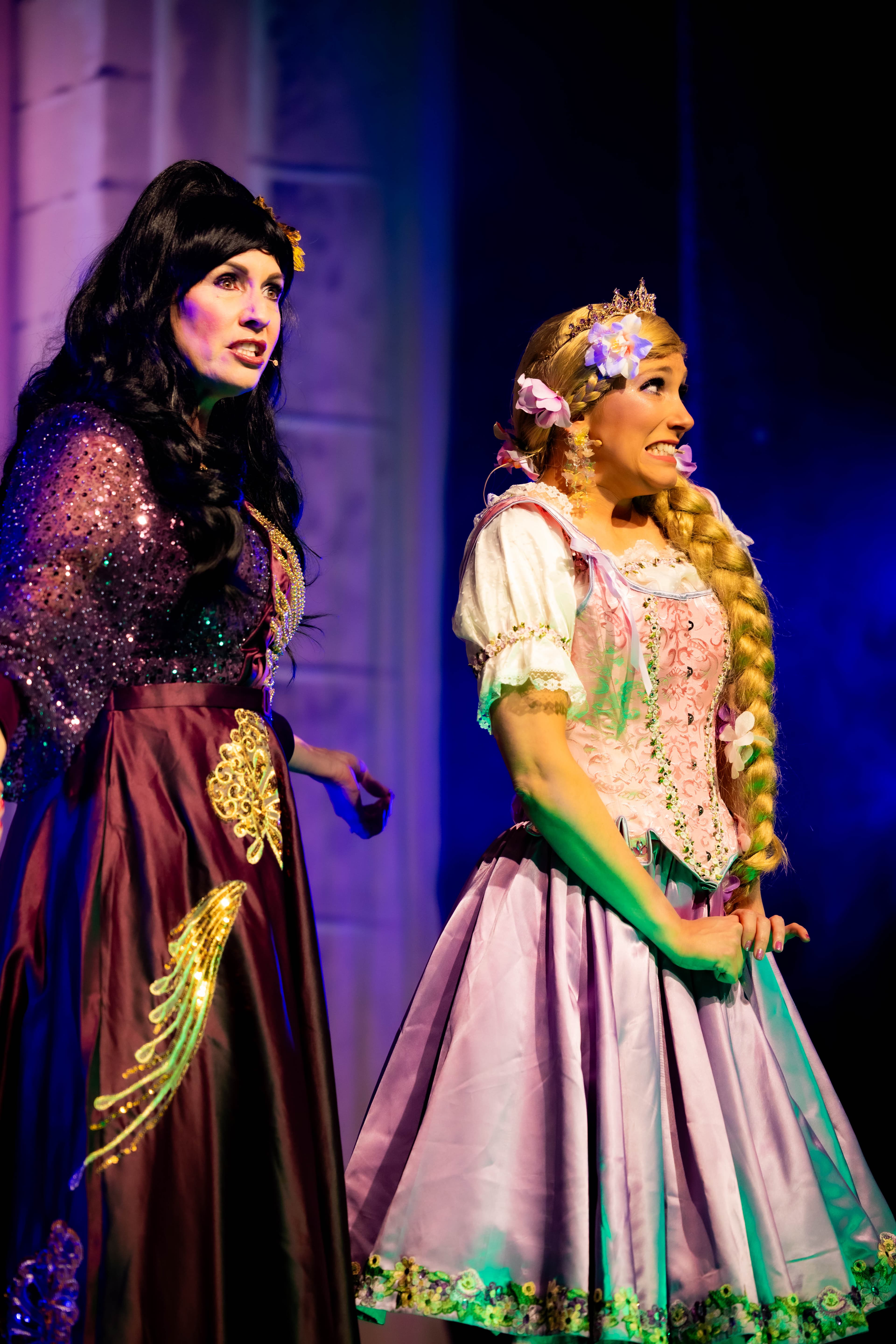 Rapunzel and Mother Gothel talk on stage. Rapunzel looks away scared.