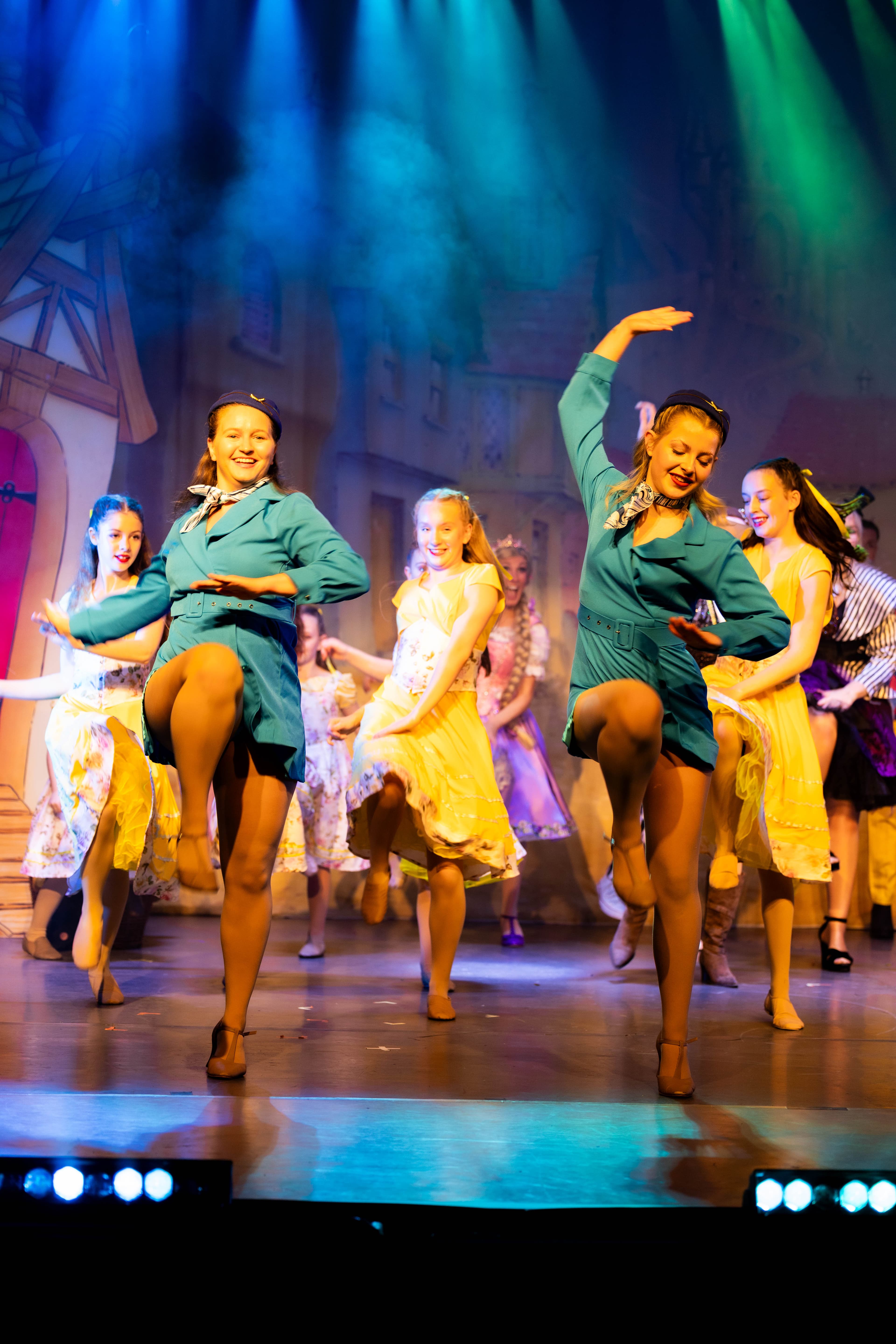 The Principal Dancers are seen dancing slapping their knees wearing flight attendant uniforms. The child cast dance behind them.